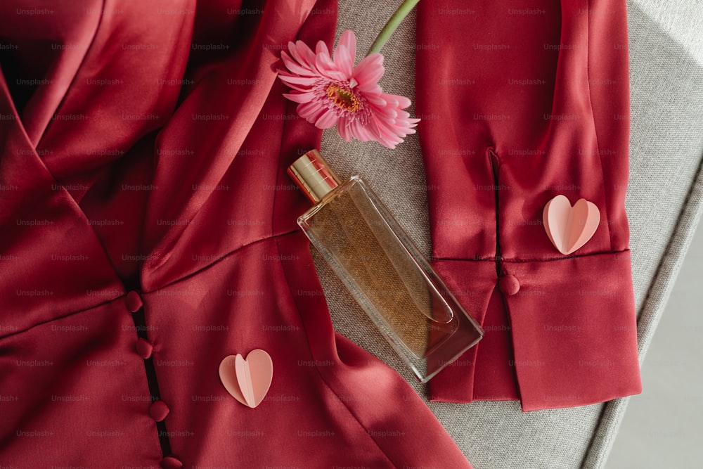 a bottle of perfume next to a pink flower