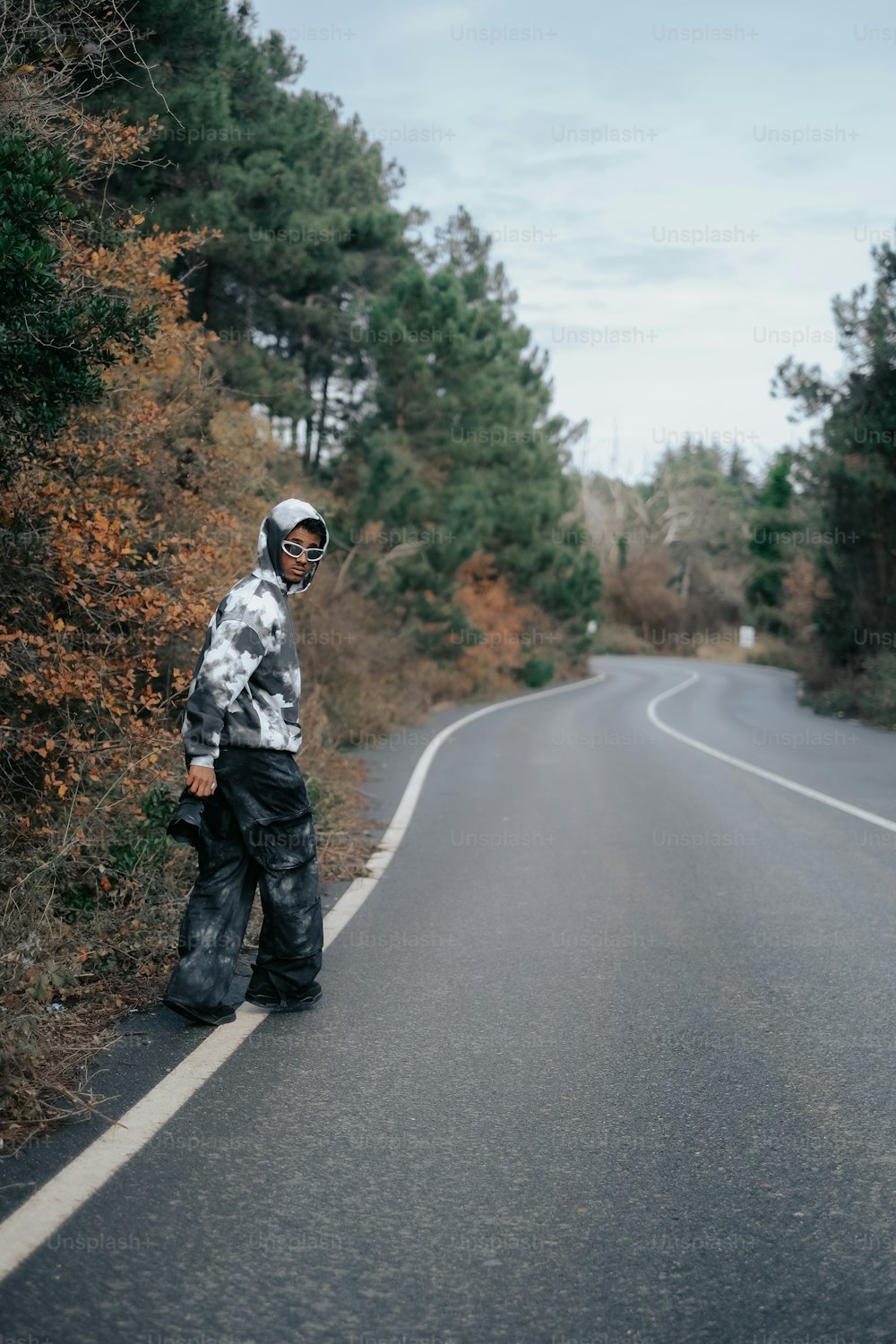 a man standing on the side of a road next to a forest