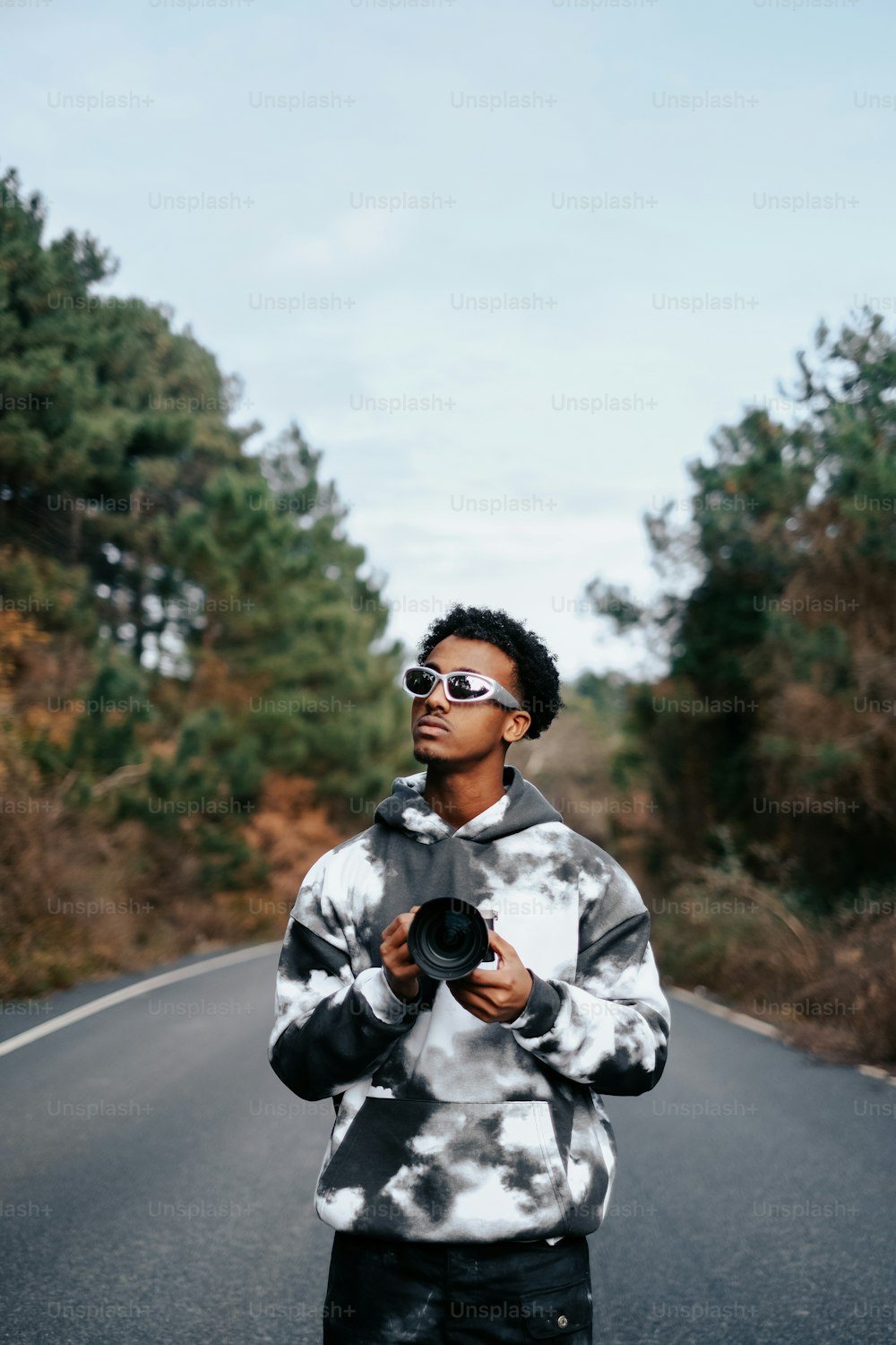 um homem de pé ao lado de uma estrada segurando uma câmera