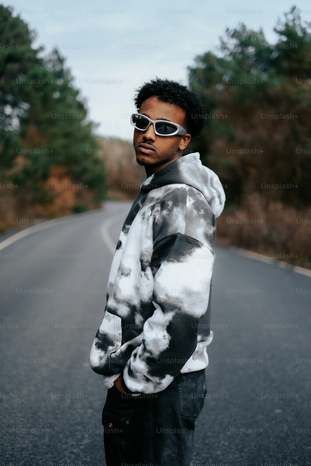 a man standing on the side of a road wearing sunglasses