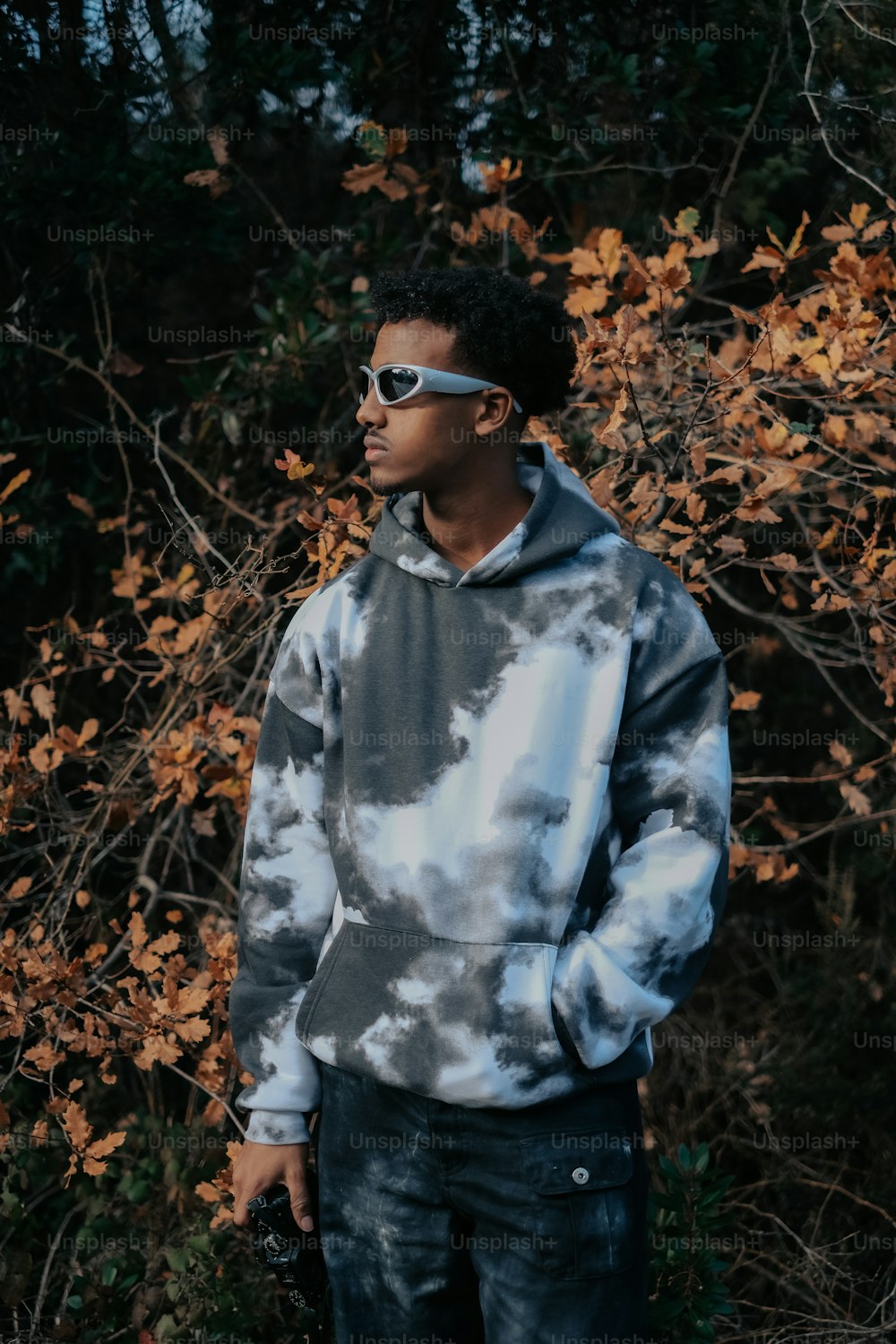 a man wearing a tie dye hoodie and sunglasses