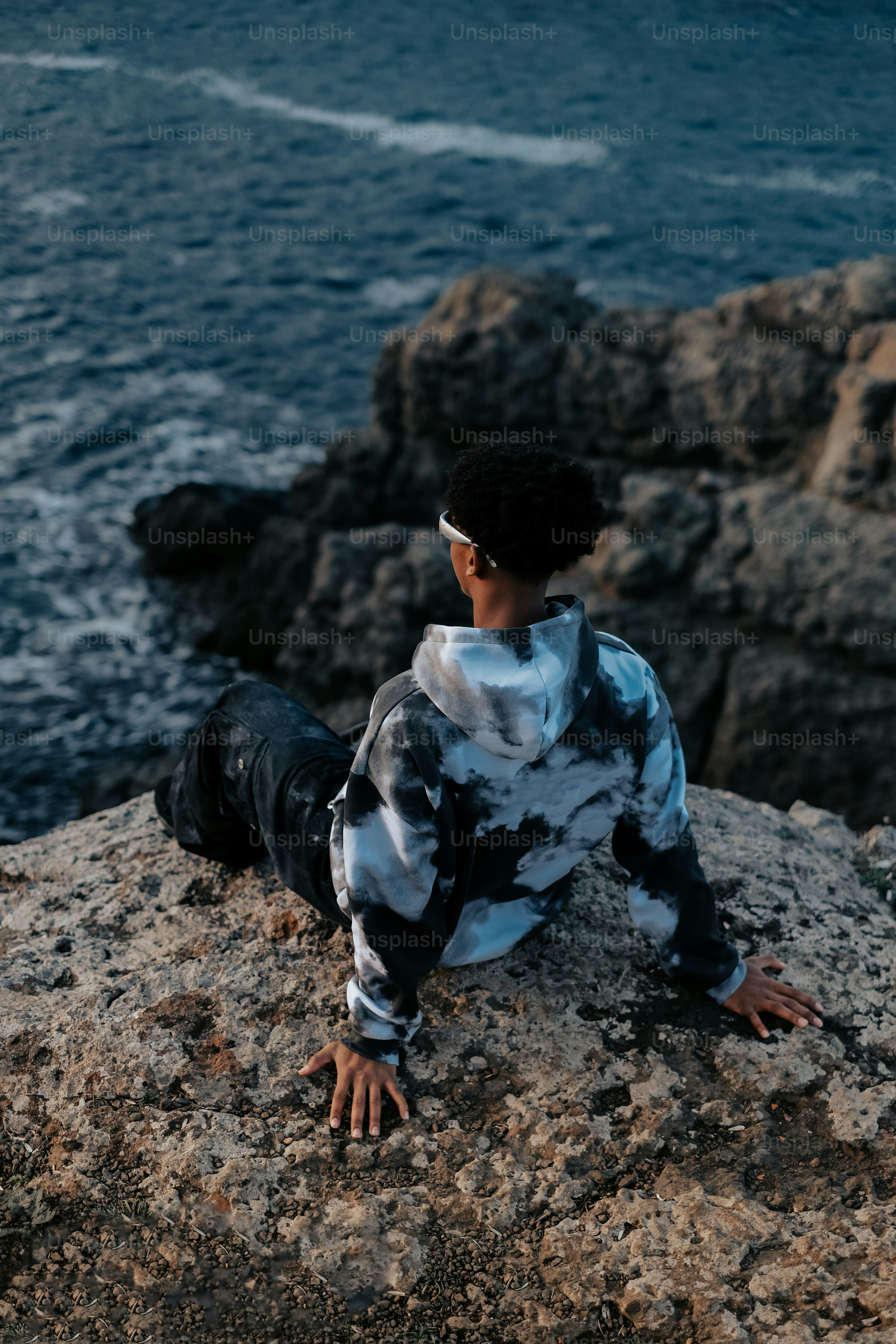 A boy sitting on a rock near the ocean photo – Fashion Image on Unsplash