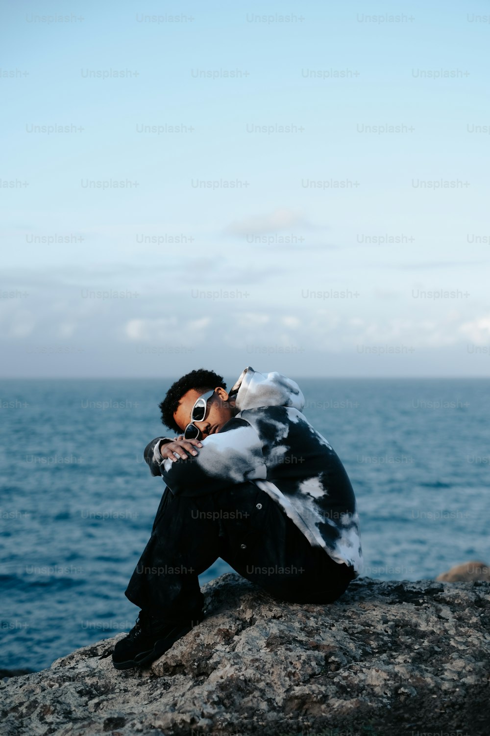 Un homme assis au sommet d’un rocher au bord de l’océan