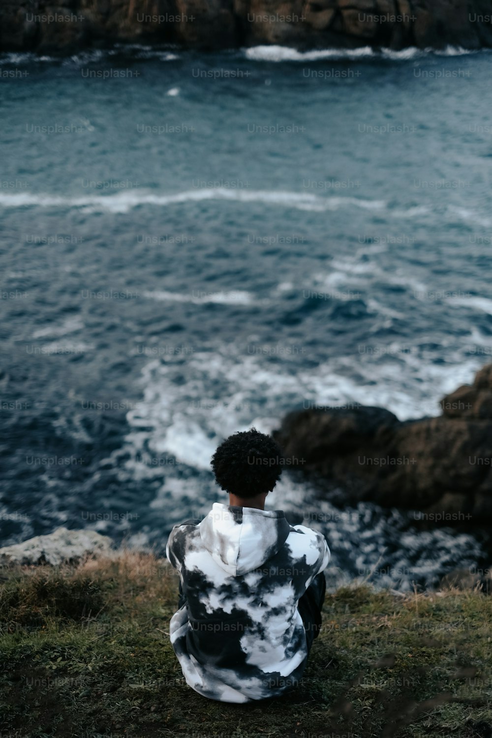 a person sitting on top of a hill near the ocean