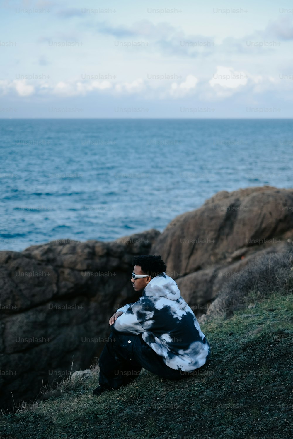 a man sitting on a hill next to the ocean