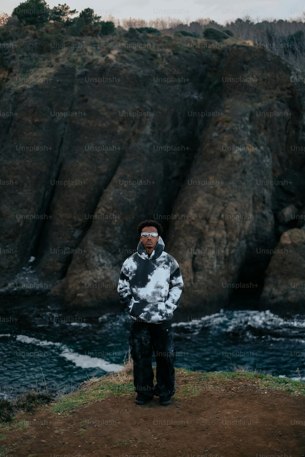 Un uomo in piedi sulla cima di una collina vicino a uno specchio d'acqua