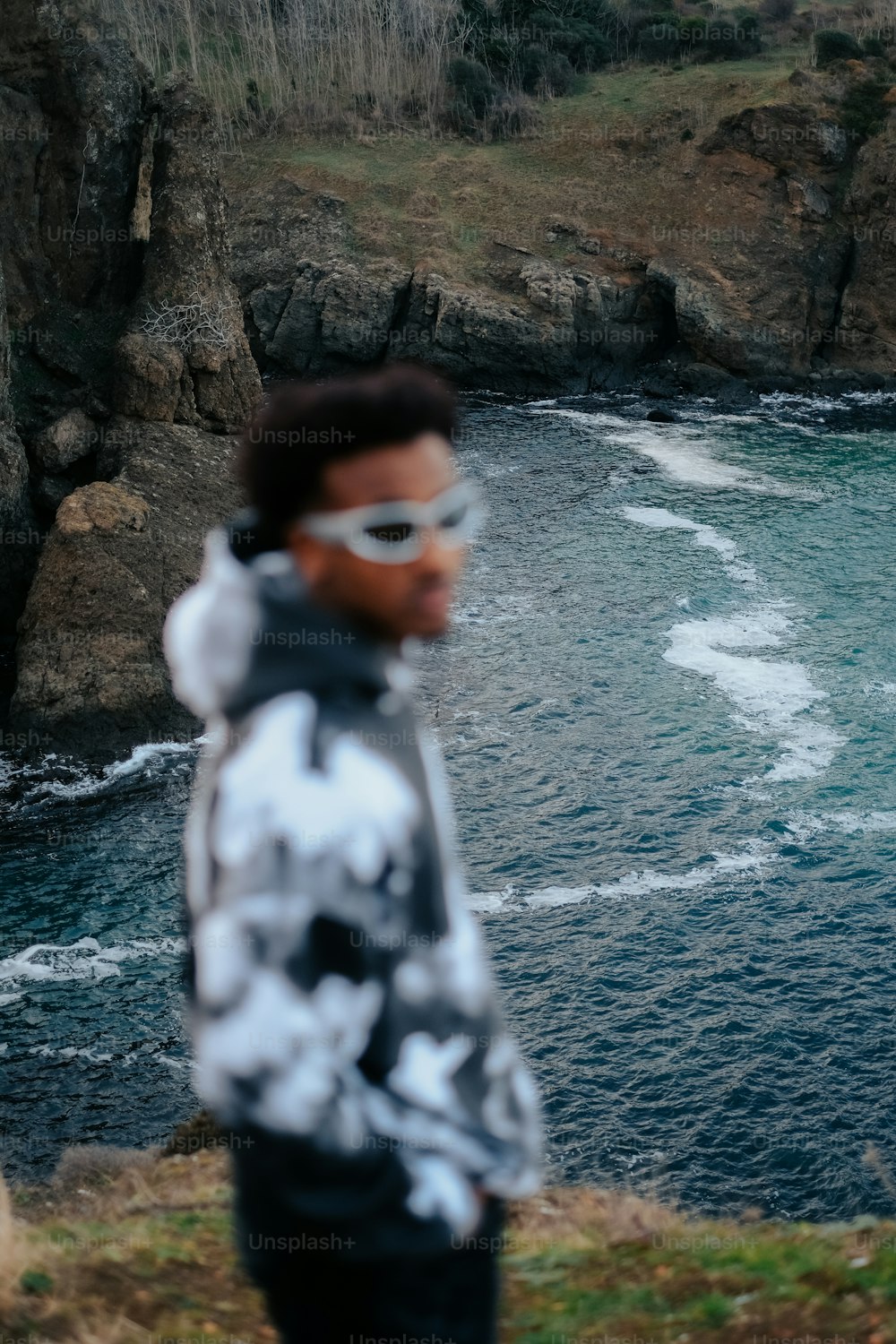 Un uomo in piedi sulla cima di una scogliera vicino all'oceano