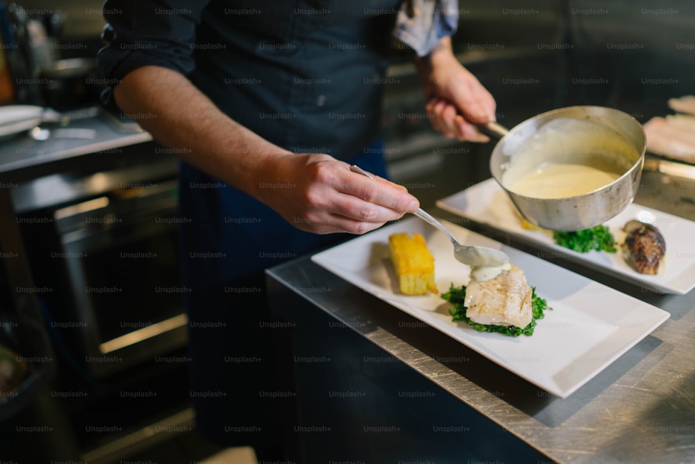 a person in a kitchen preparing food on a plate