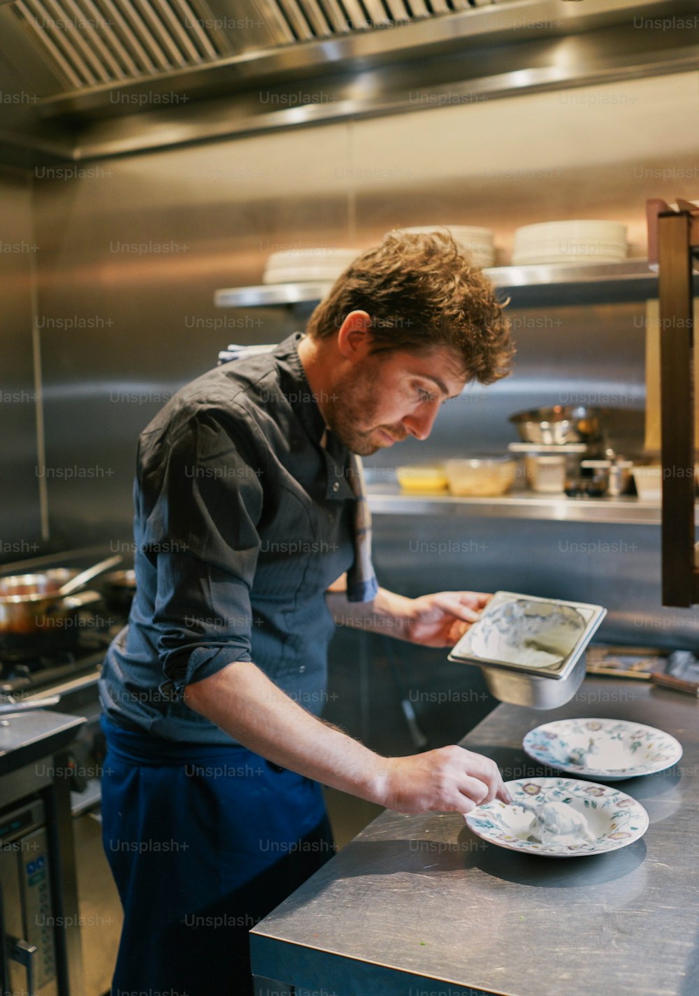 a man in a kitchen preparing food on a plate