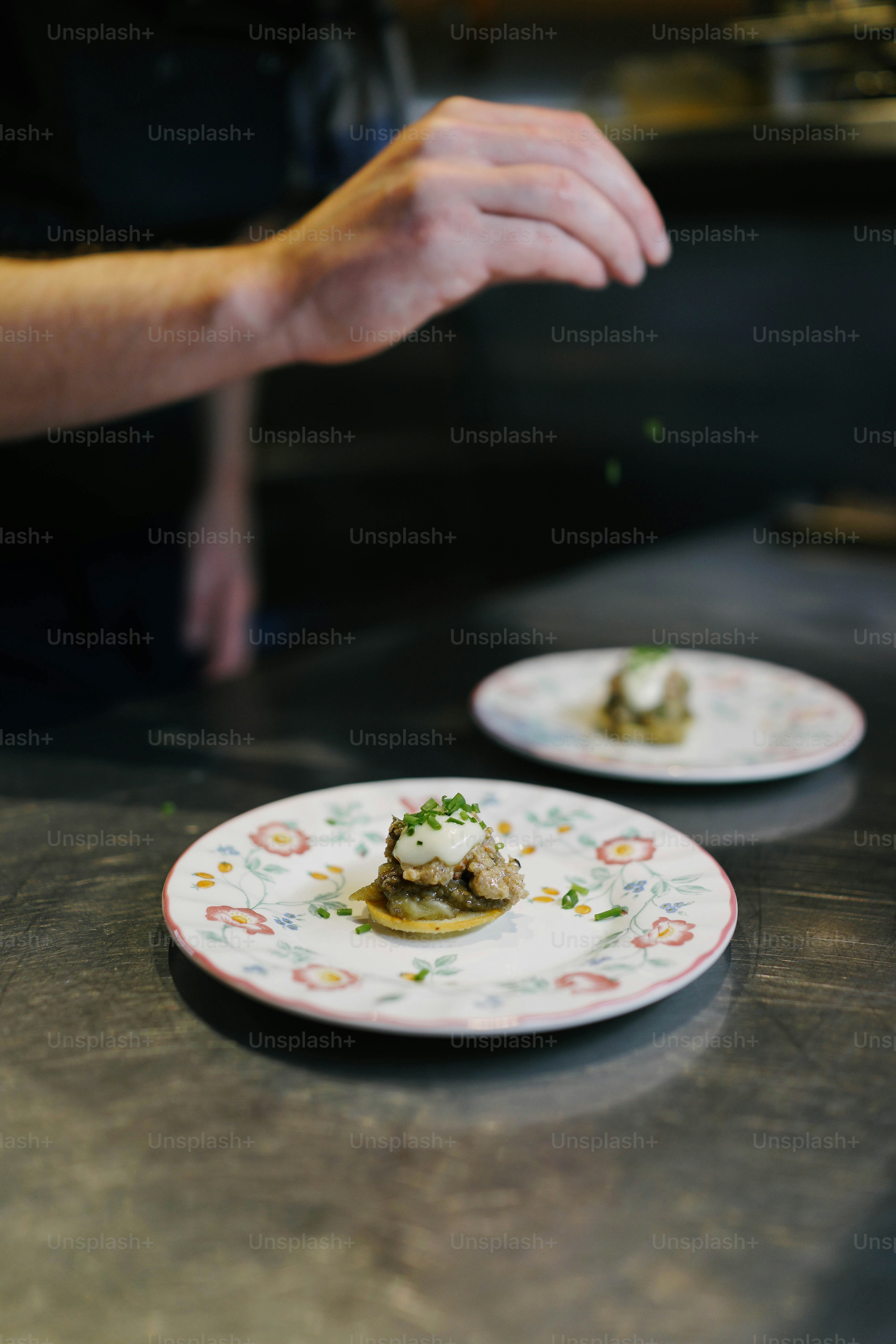 A person reaching for a piece of food on a plate photo – Chef Image on ...