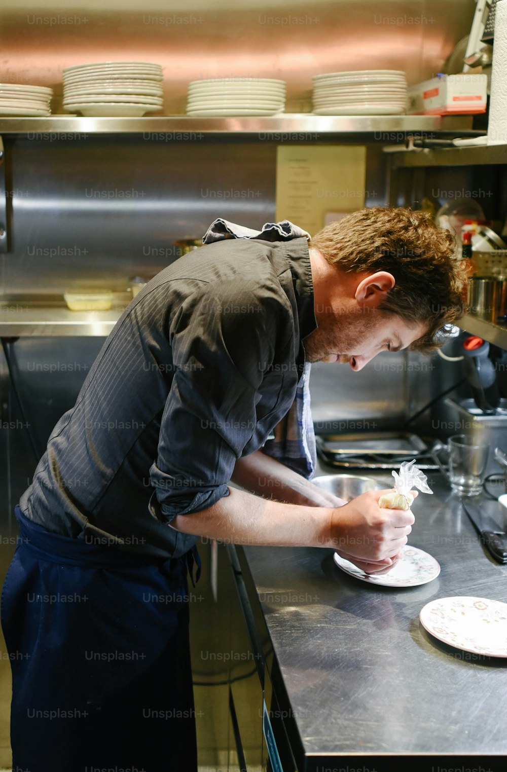 a man in a kitchen preparing food on a plate