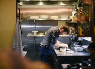 um homem em pé em uma cozinha preparando comida