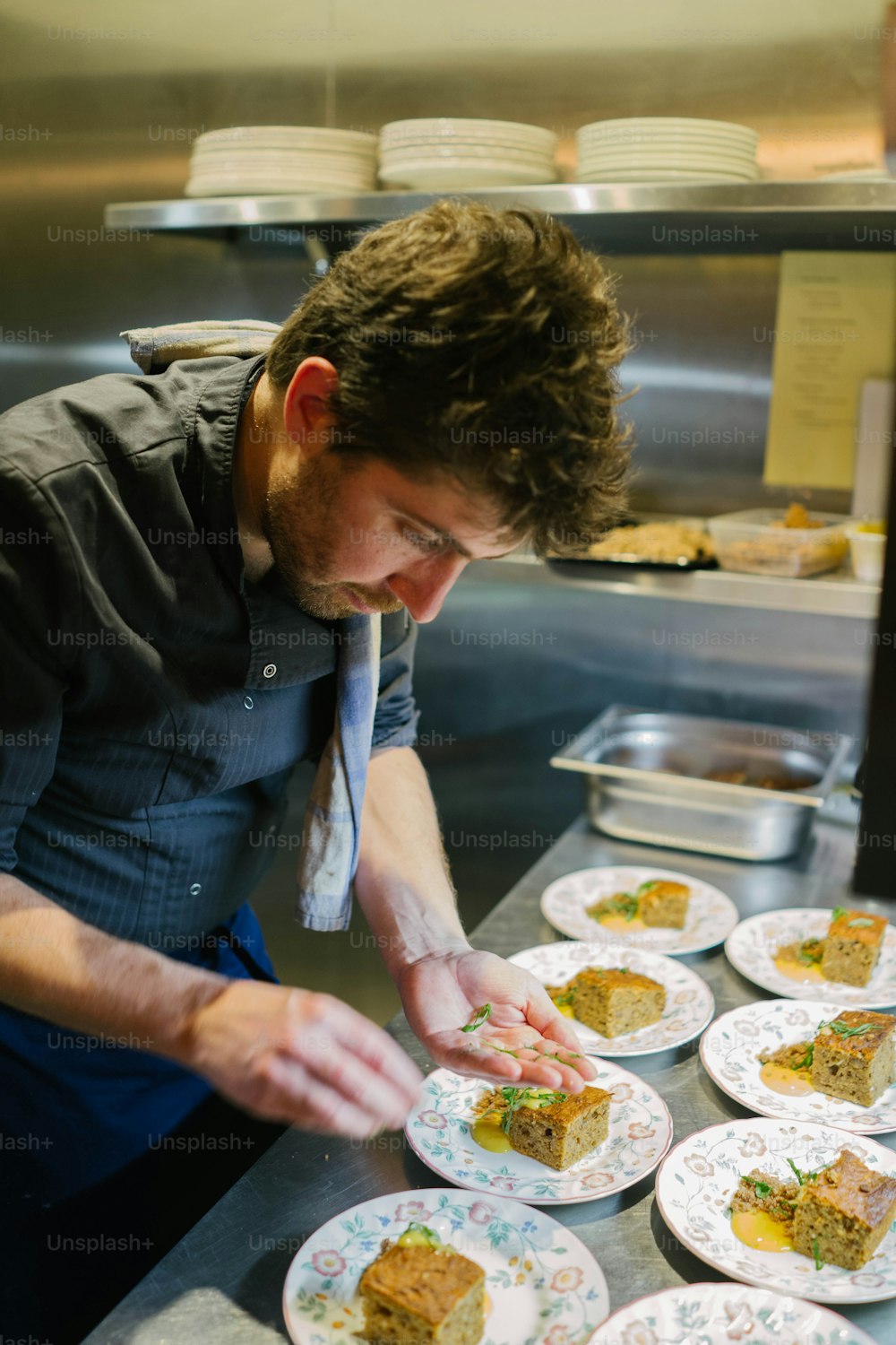 um homem em uma cozinha preparando comida em pratos