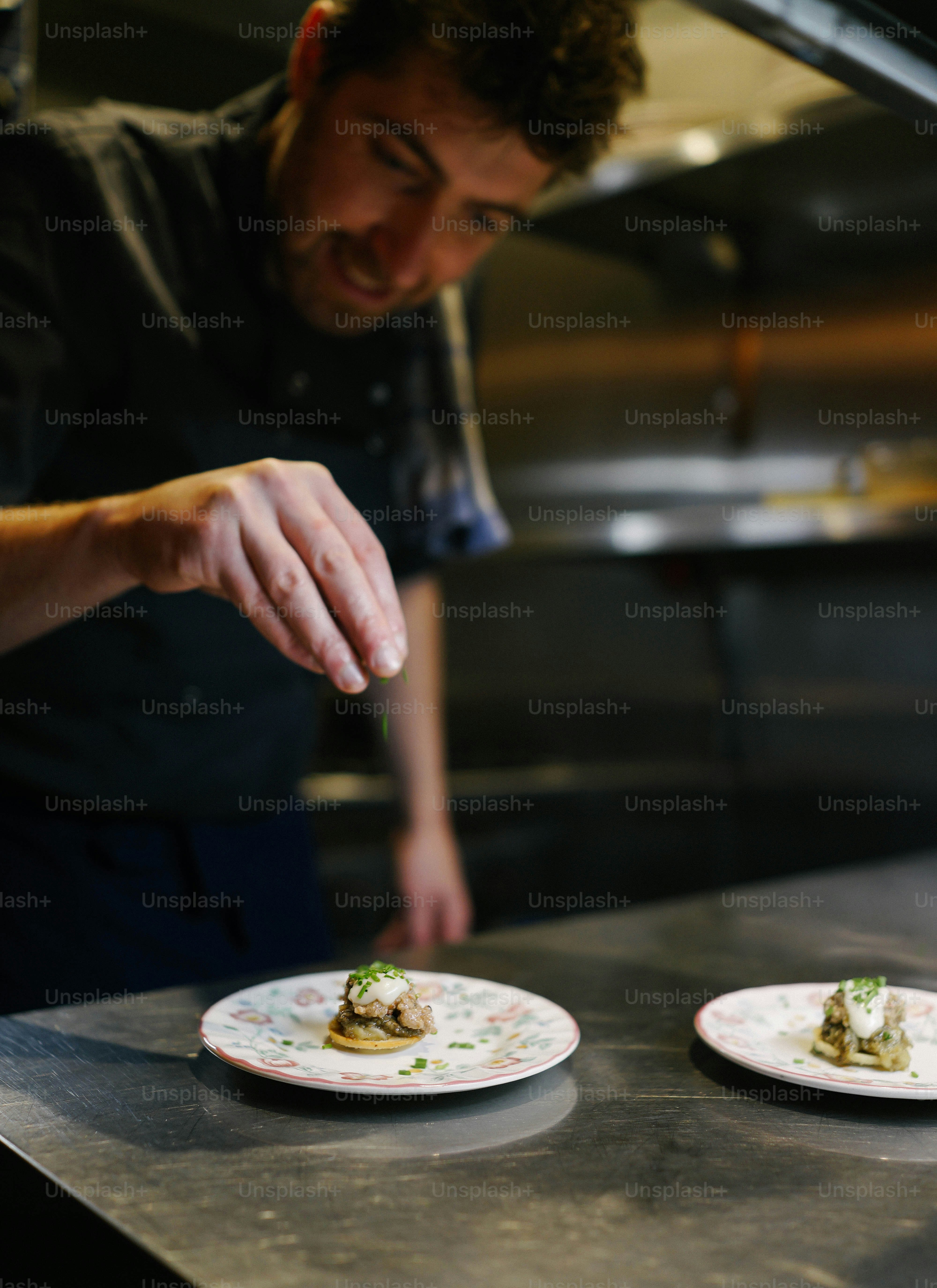 Ein Mann in einer Küche bereitet Essen auf einem Teller zu