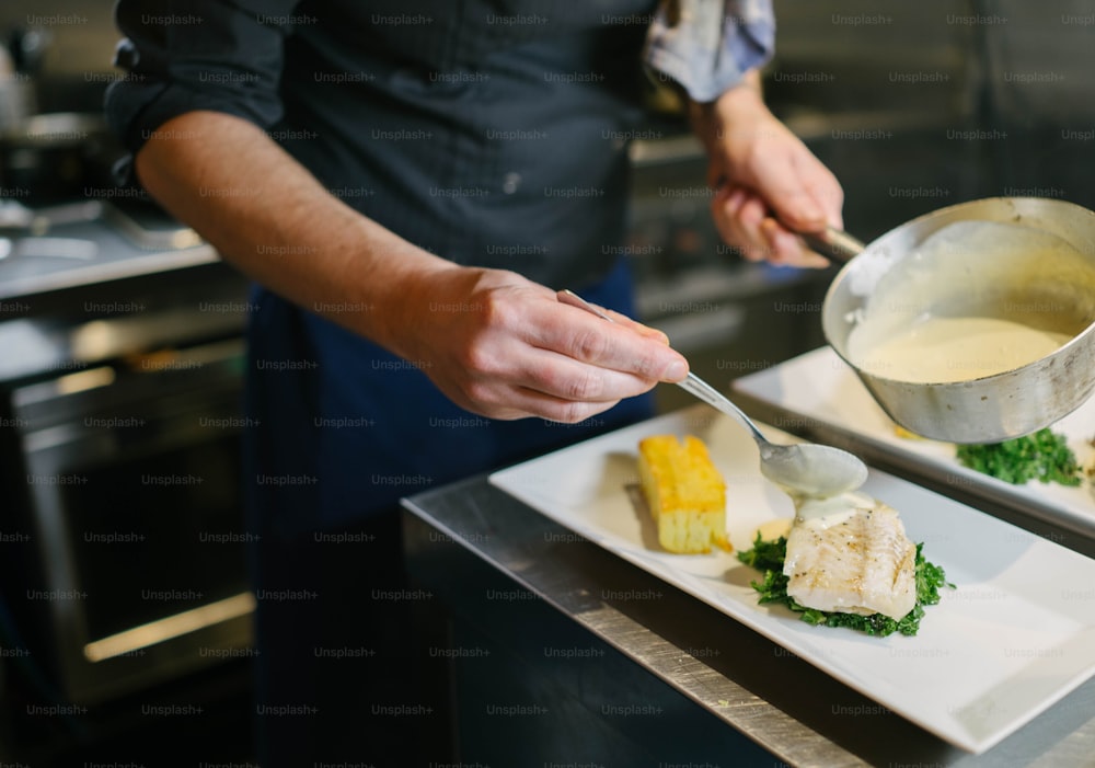 una persona in una cucina che prepara il cibo su un piatto