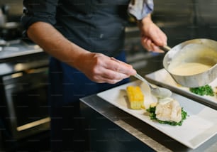 a person in a kitchen preparing food on a plate