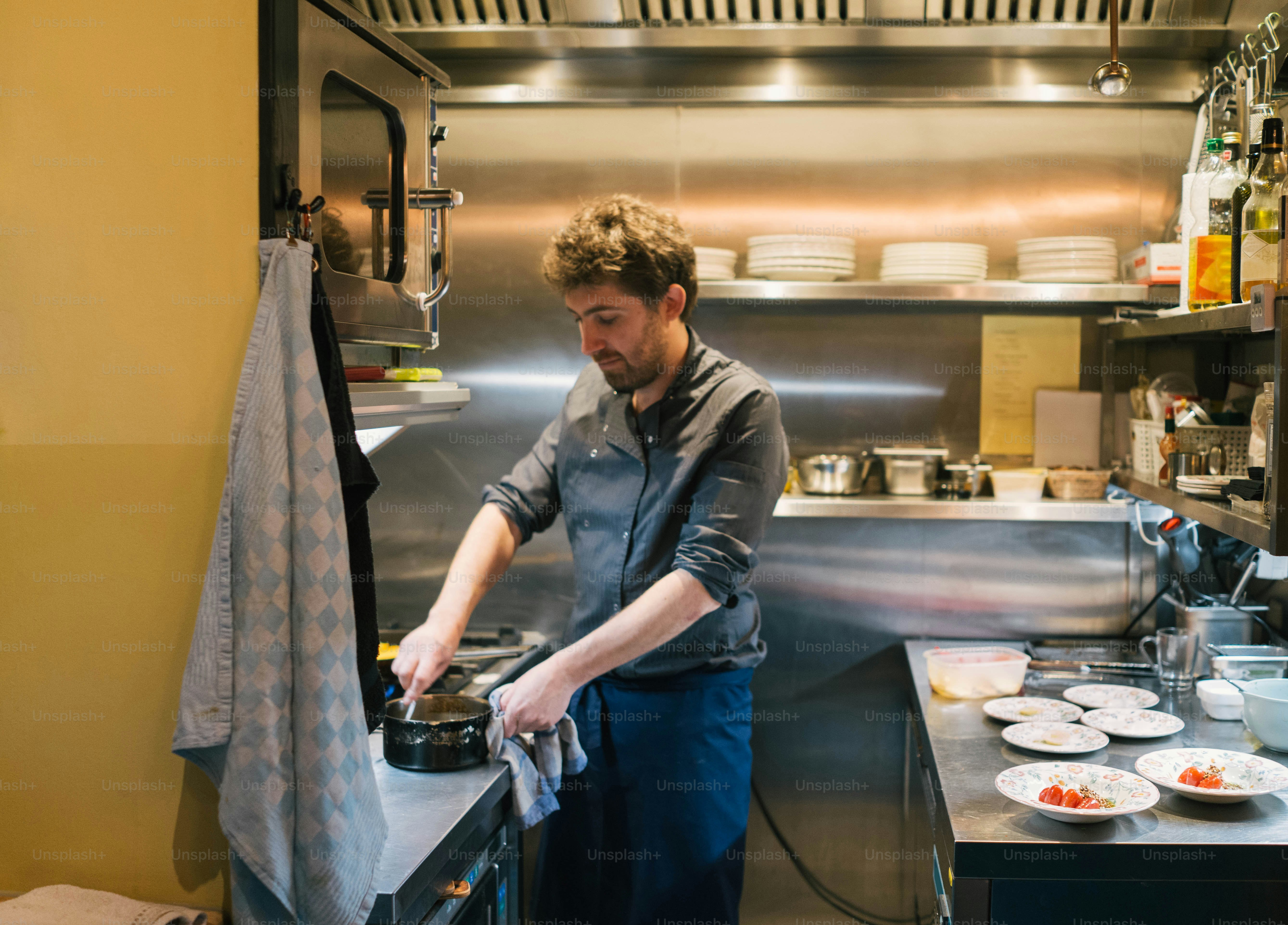 Ein Mann in einer Küche bereitet Essen auf einem Herd zu