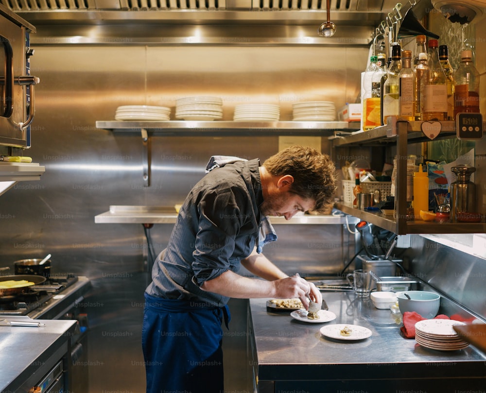 a man in a kitchen preparing food on a plate