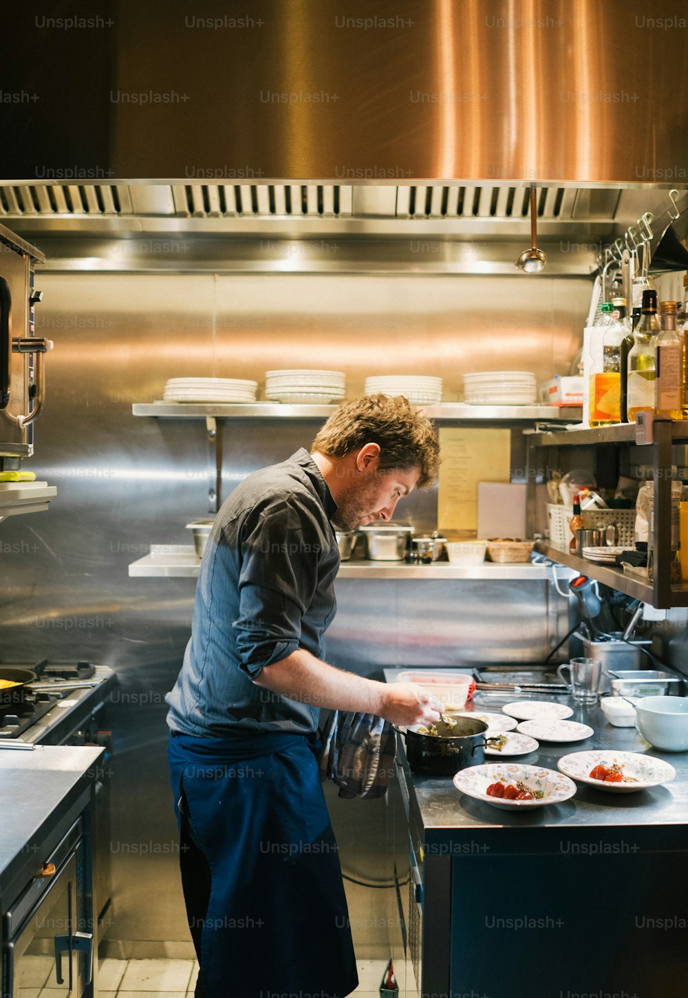 um homem preparando comida em uma cozinha ao lado de um fogão
