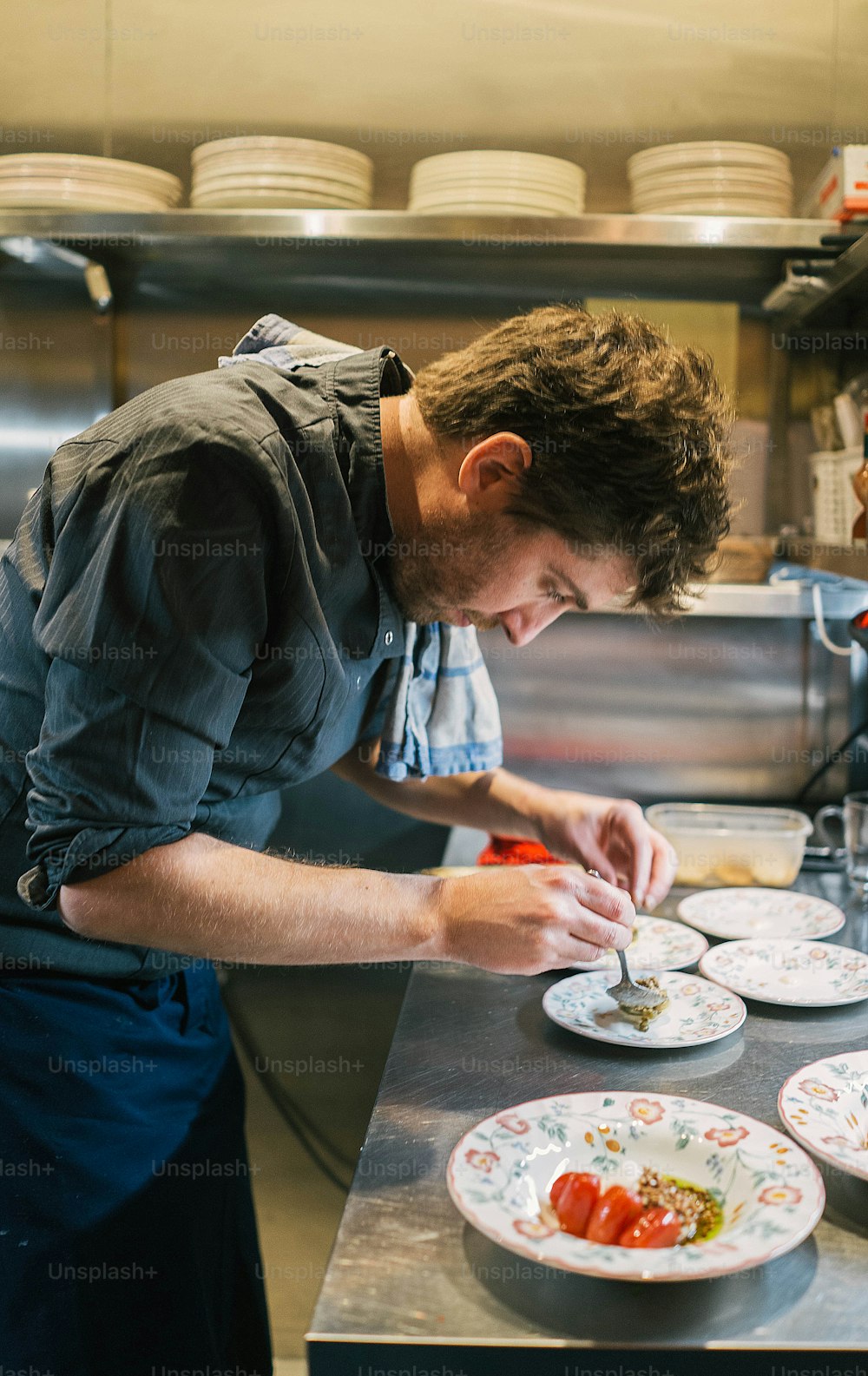 um homem em uma cozinha preparando comida em um prato