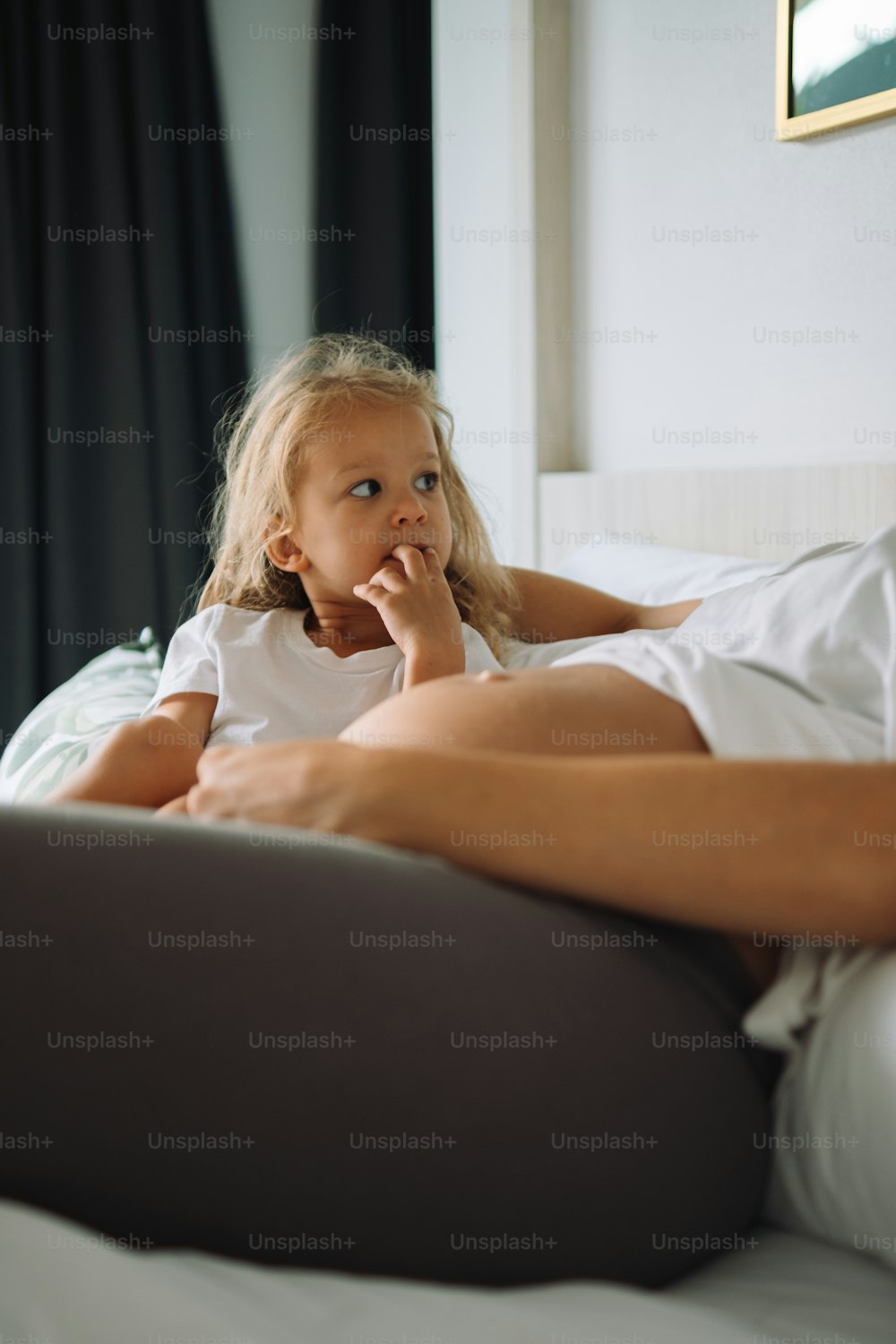 une petite fille allongée sur un lit avec sa main sur le menton