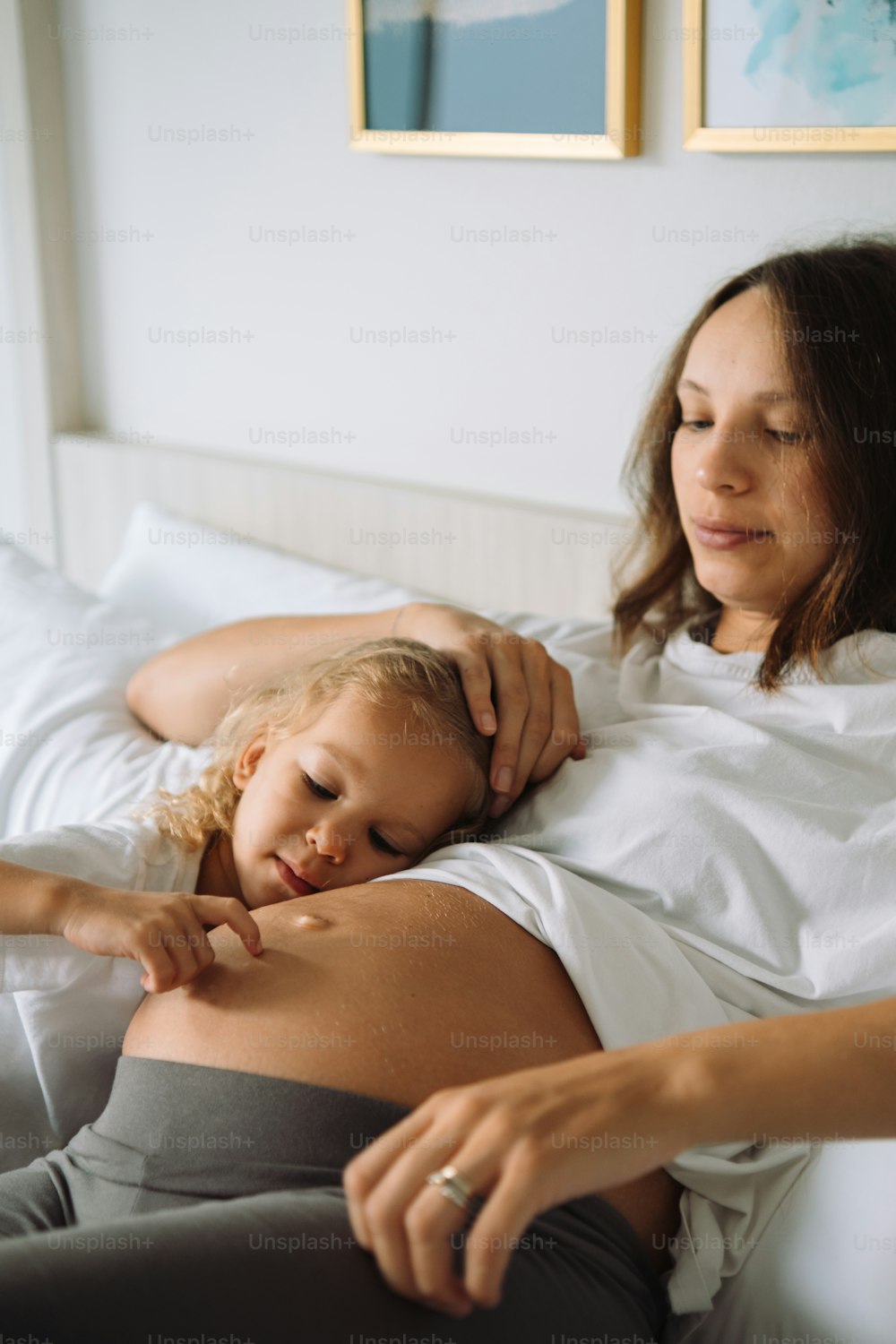 a pregnant woman laying in bed with a child