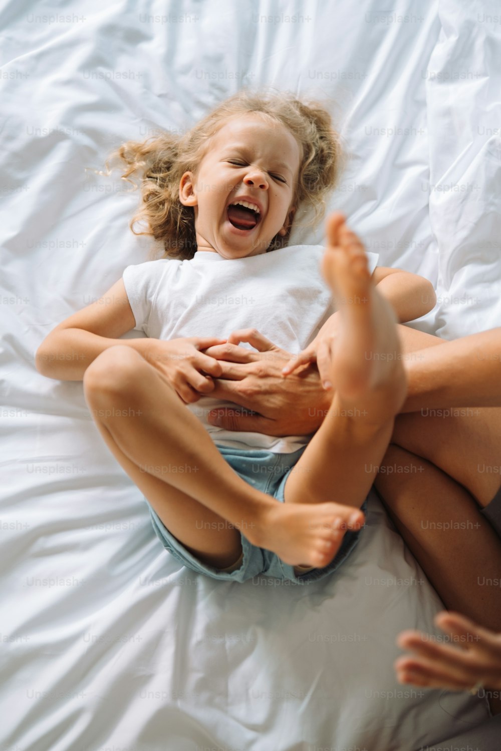 a little girl sitting on a bed with her feet up