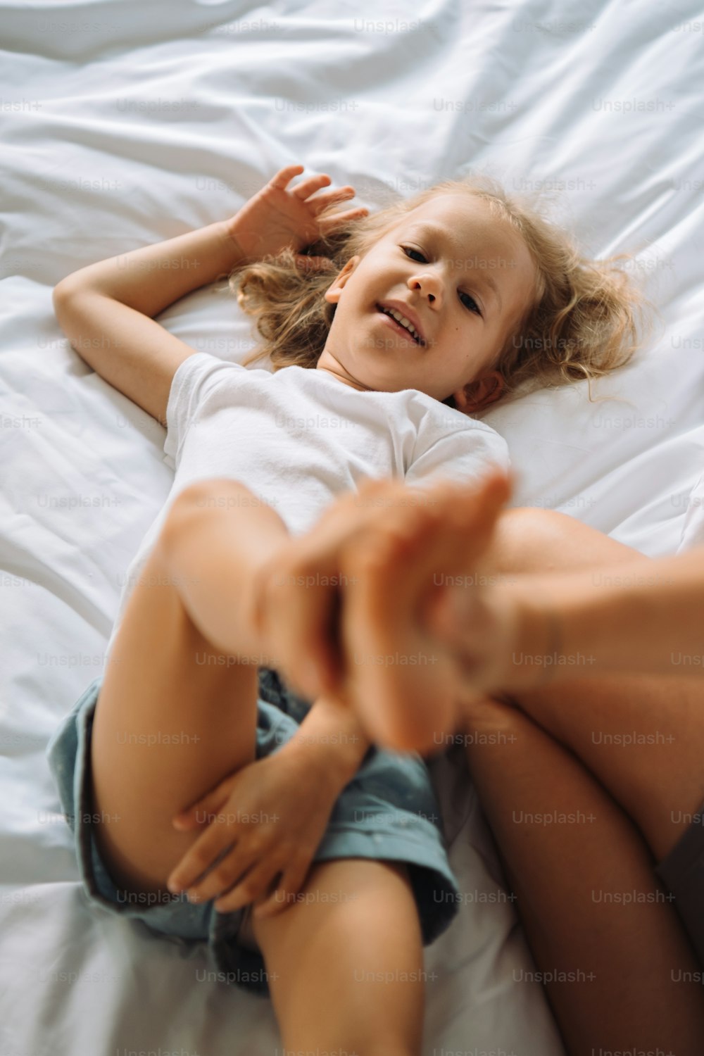 a little girl laying on top of a white bed