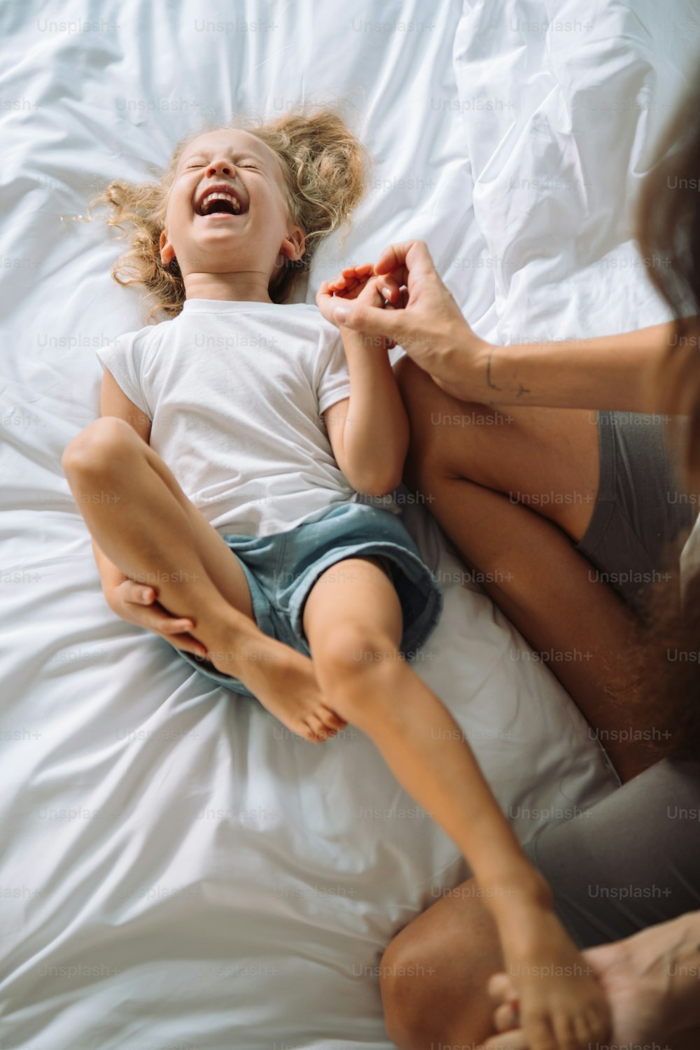 a little girl laying on a bed with her mother