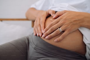 eine schwangere Frau mit den Händen auf dem Bauch