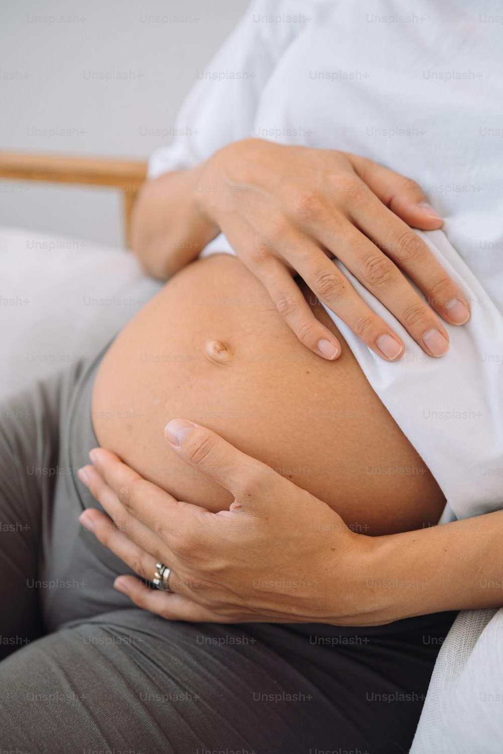 a pregnant woman holding her belly while sitting on a couch