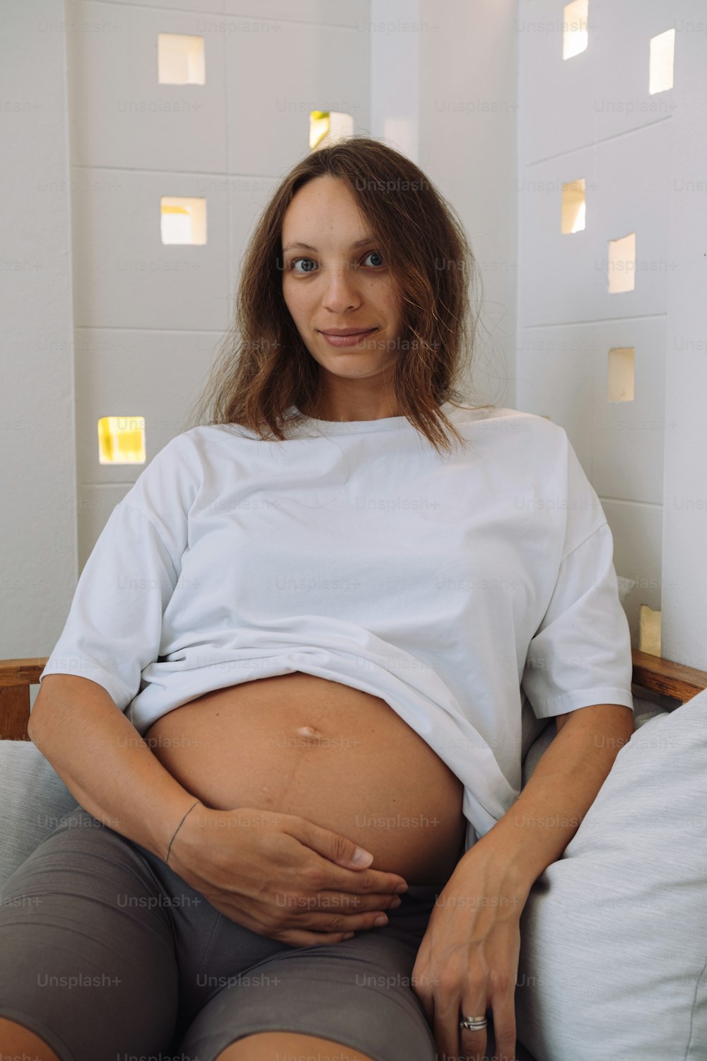 Una donna incinta è seduta su un divano
