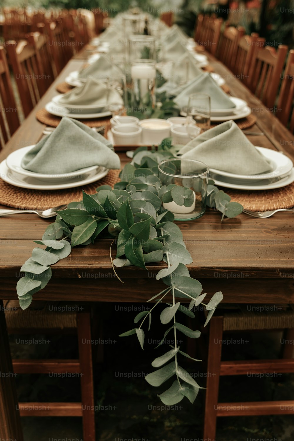 ein langer Tisch mit Gedecken und Grün