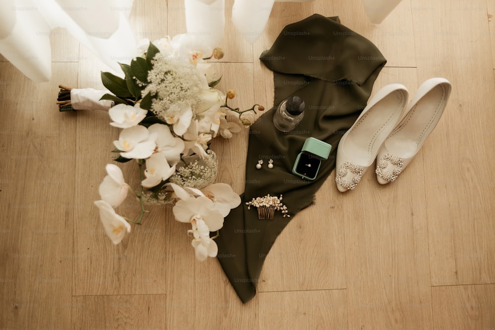 um buquê de flores e um par de sapatos em um piso de madeira