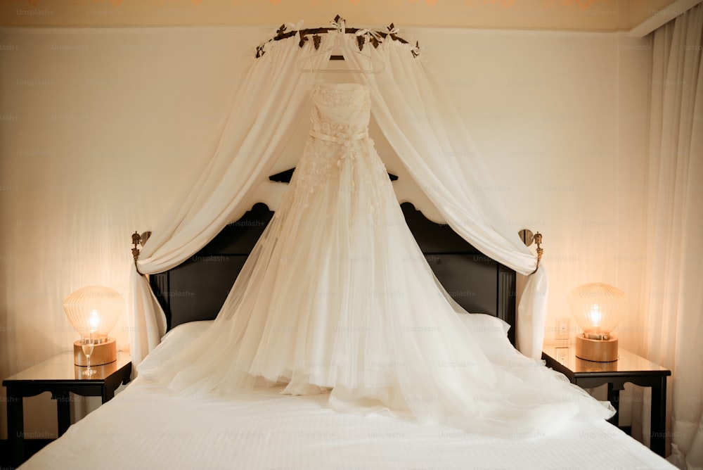 a wedding dress is hanging on a bed