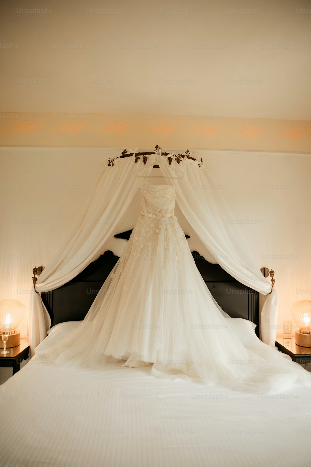 a wedding dress is hanging on a bed