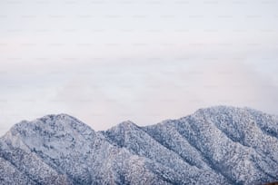 a group of mountains covered in snow under a cloudy sky