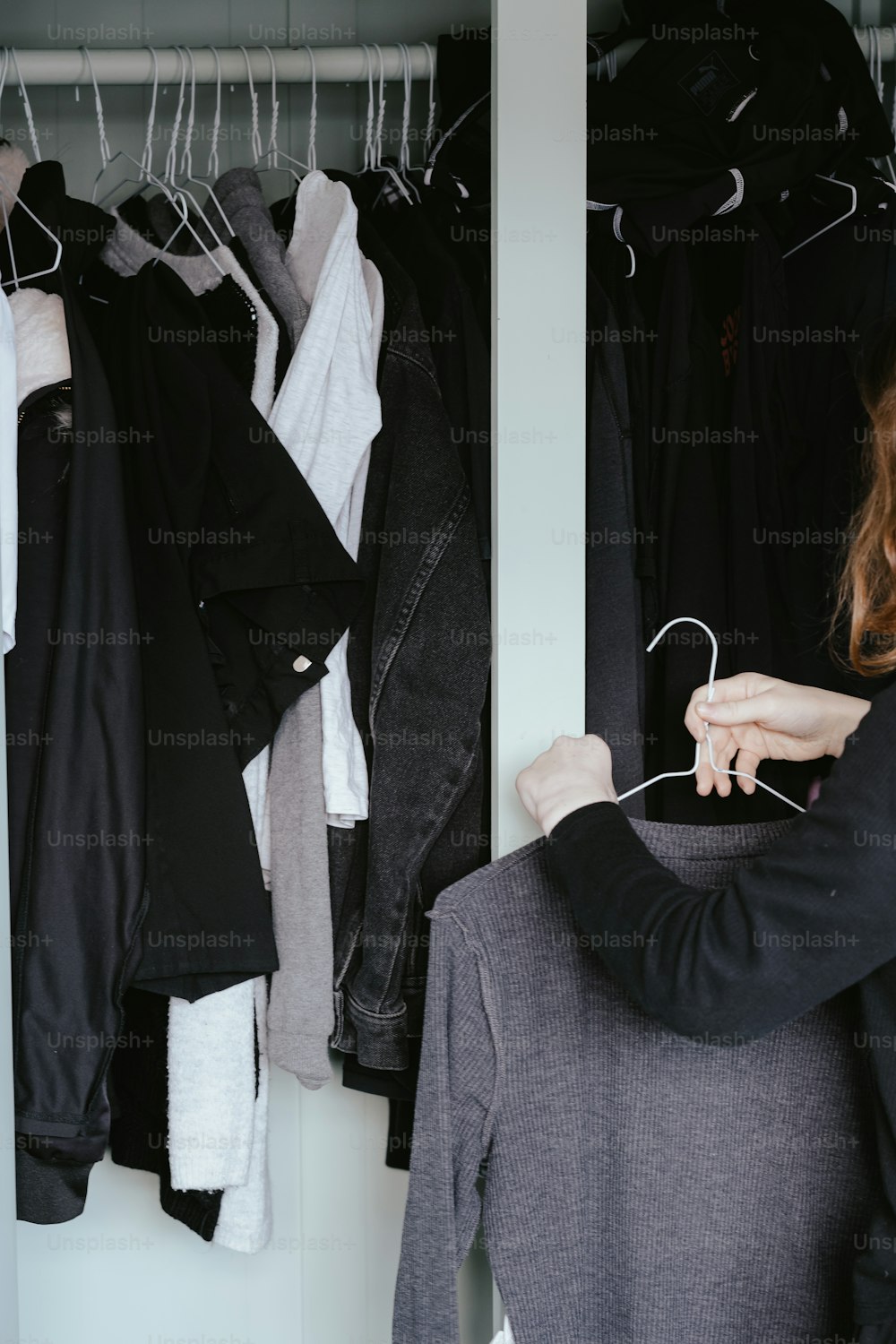 uma mulher olhando para as roupas penduradas em um rack