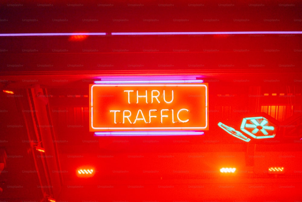 um sinal de néon vermelho que diz através do tráfego