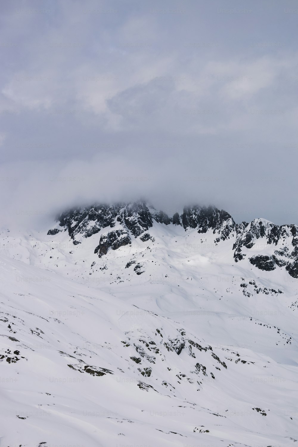 曇り空の下で雪と雲に覆われた山
