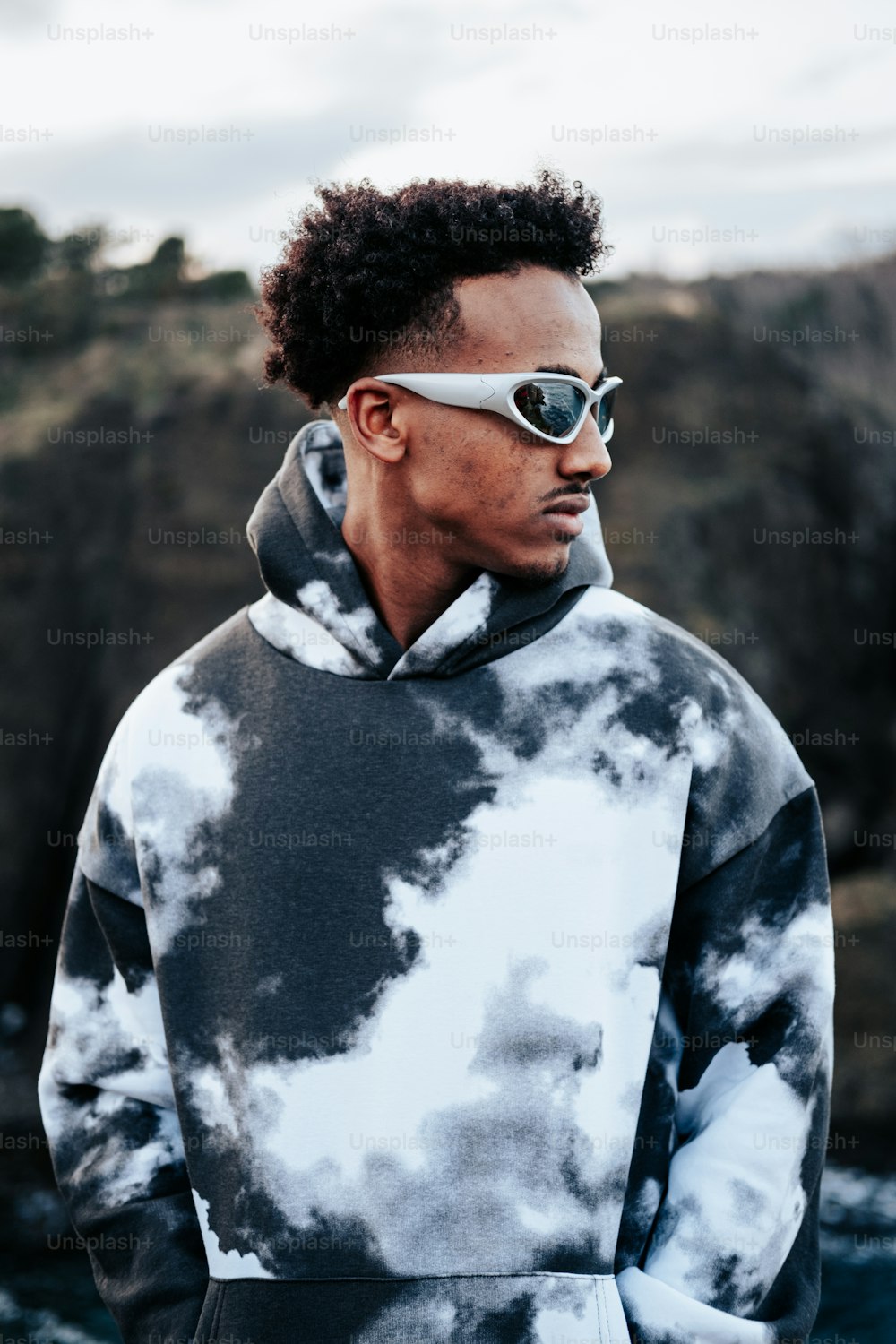 a man wearing a tie dye hoodie and sunglasses