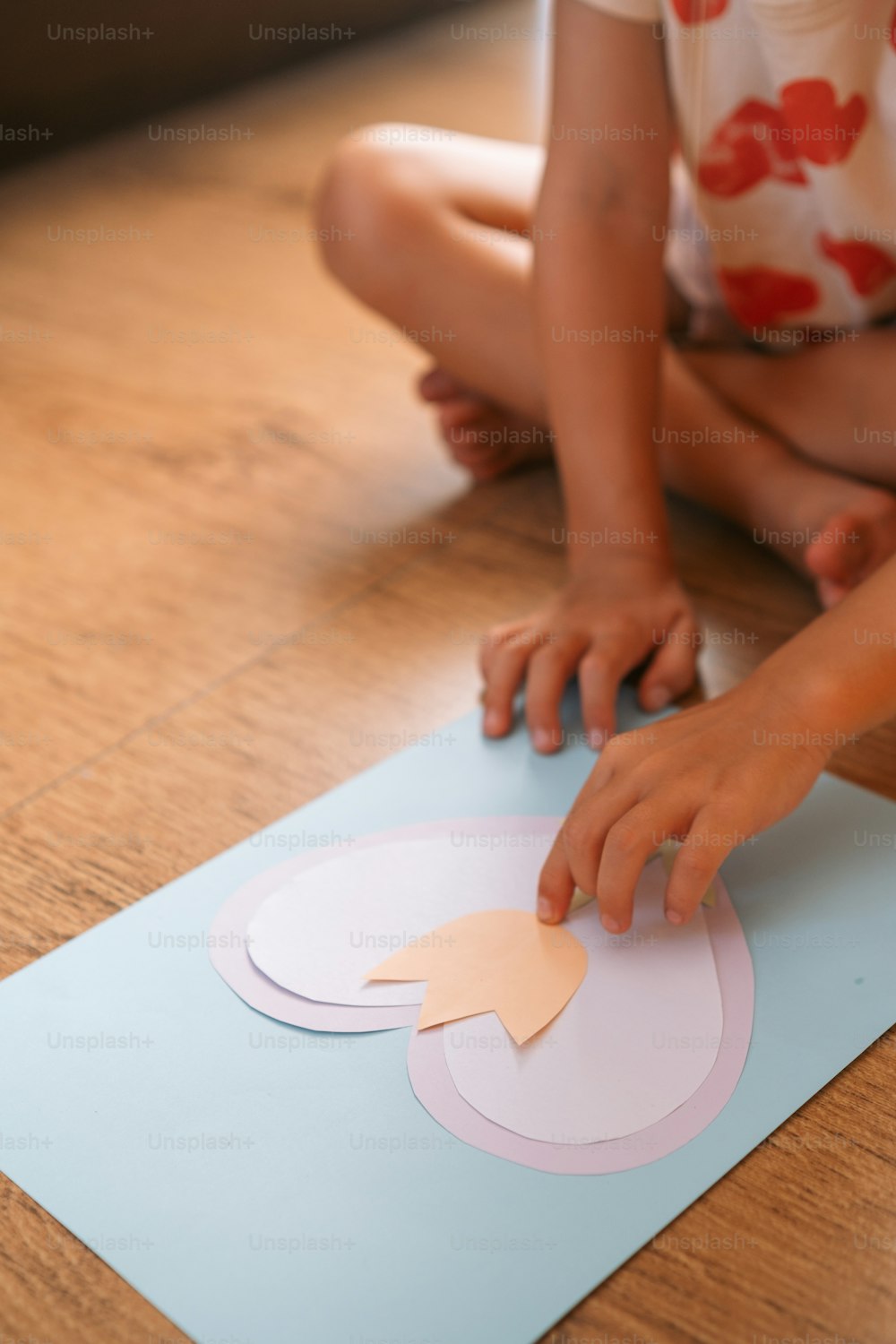a young girl sitting on the floor making a cutout of a flower