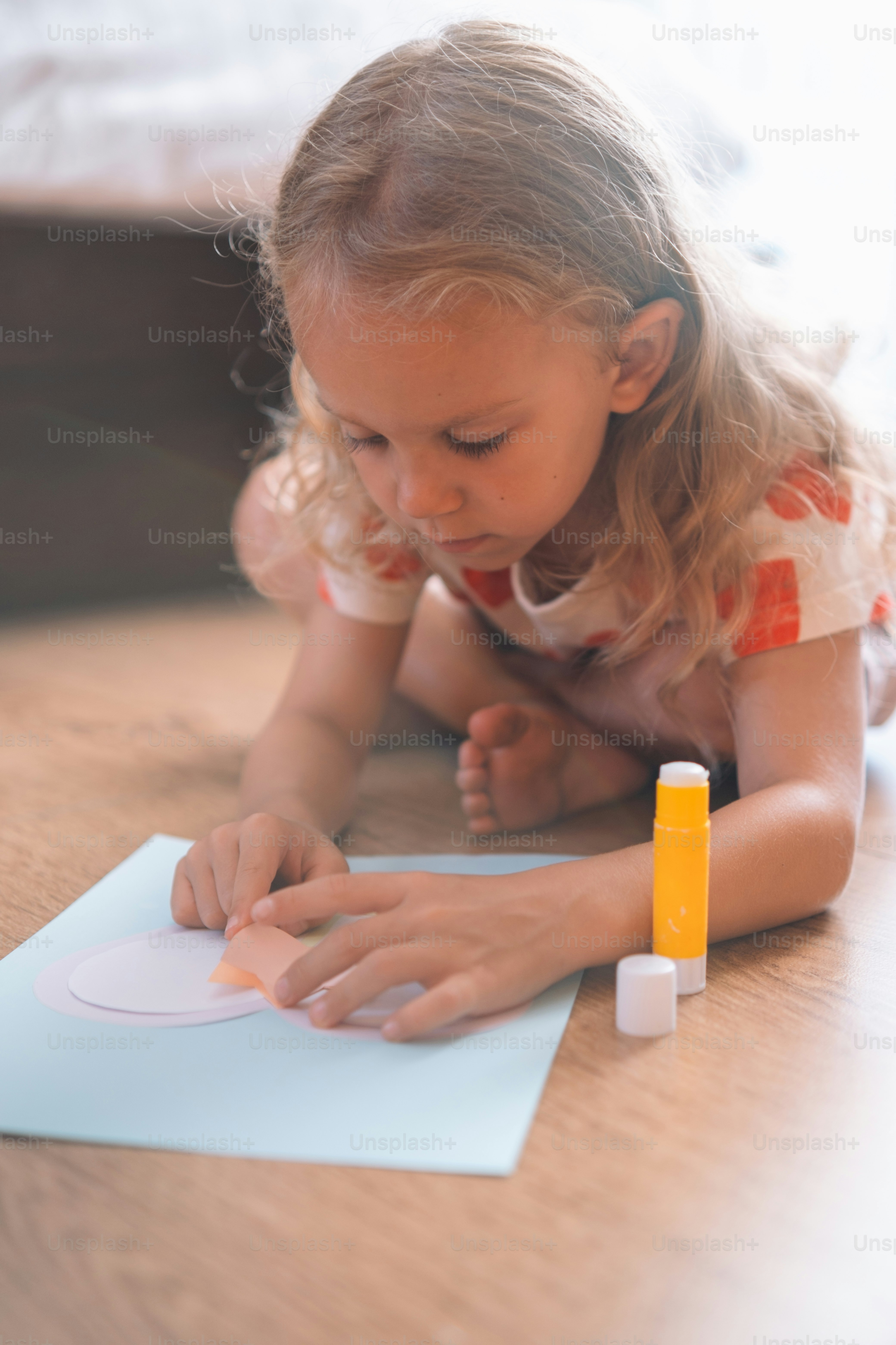una bambina che si sdraia sul pavimento disegnando su un pezzo di carta