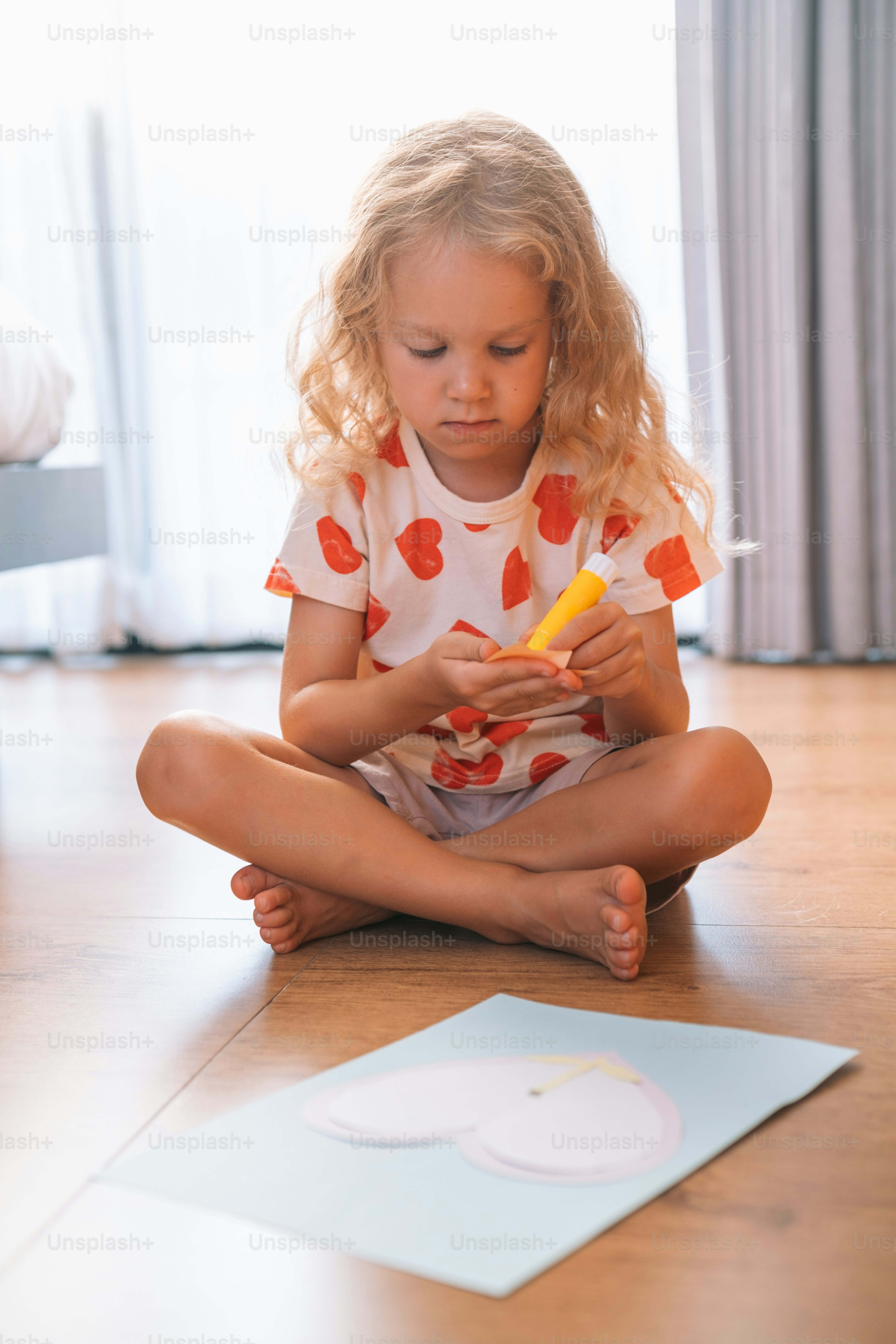 una bambina seduta sul pavimento che gioca con una penna