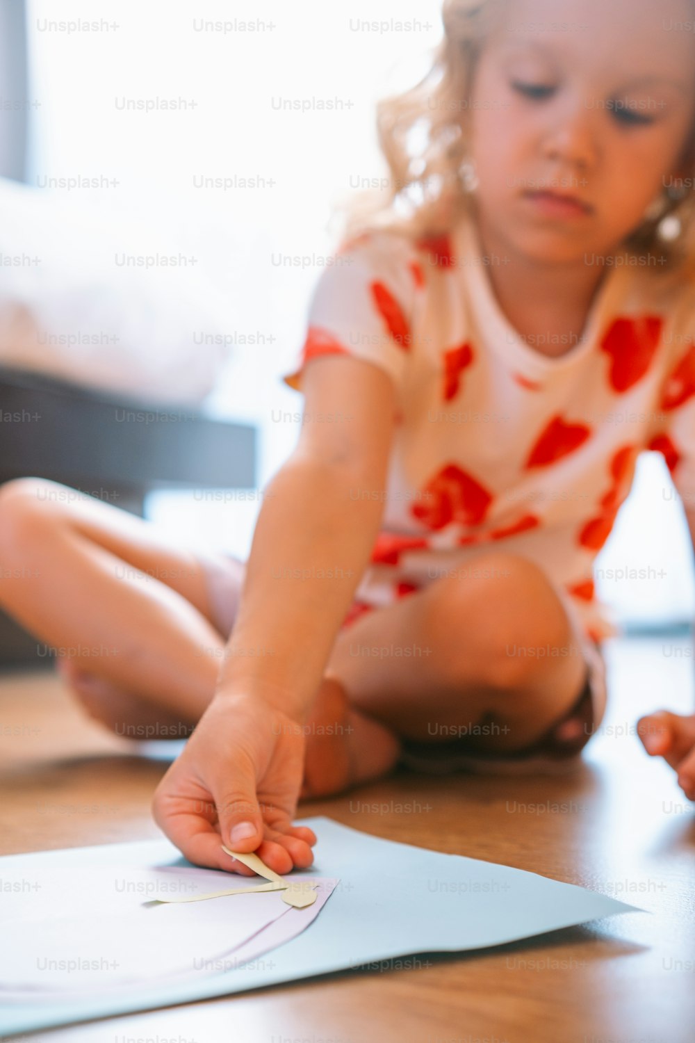 a little girl sitting on the floor playing with a piece of paper