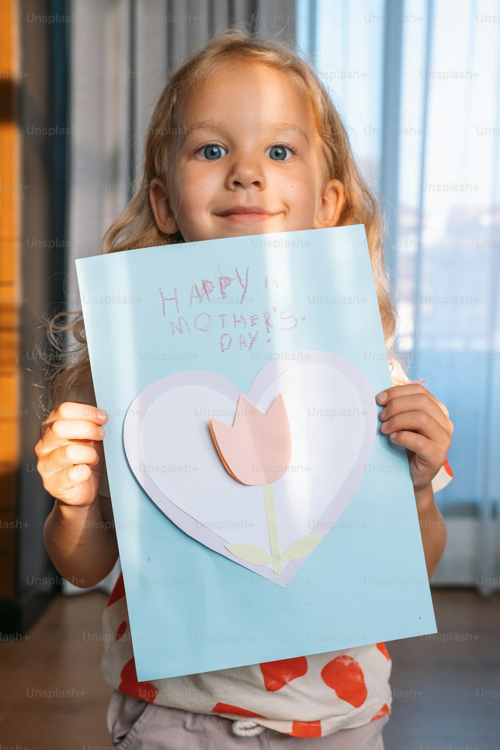 a little girl holding a happy mother's day card