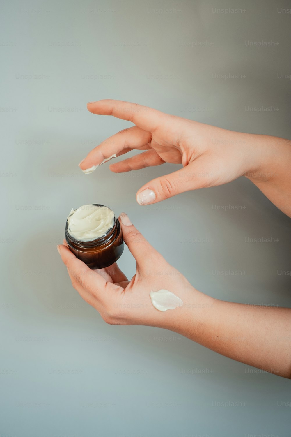 a person holding a jar of cream in their hand