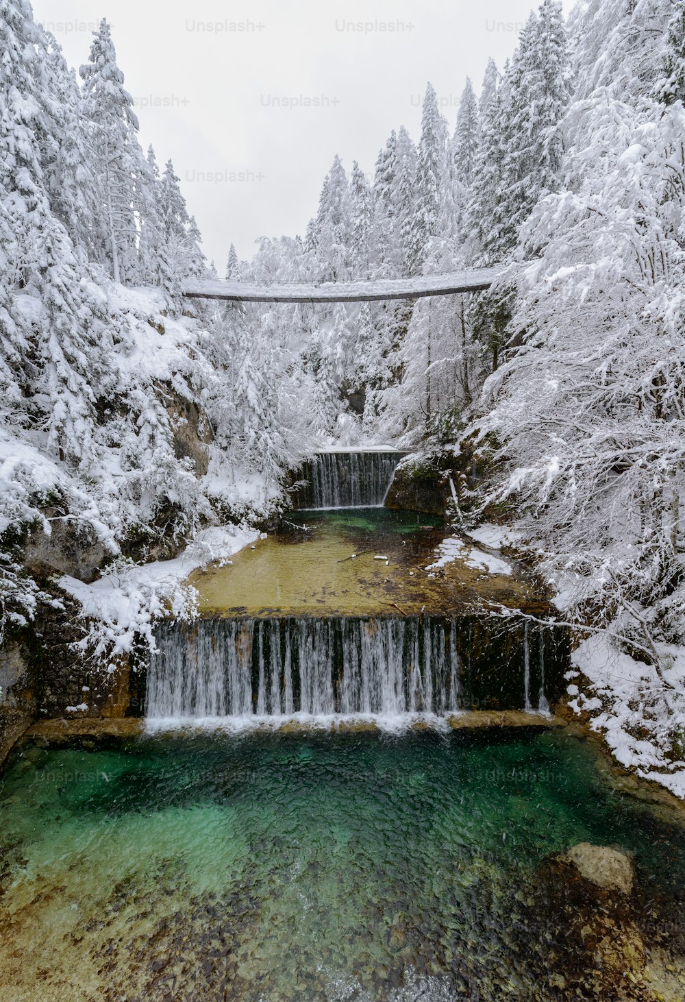 a waterfall in the middle of a snowy forest