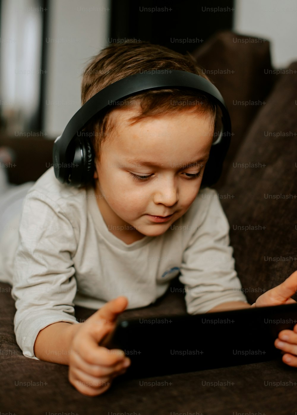 a little boy laying on a couch wearing headphones