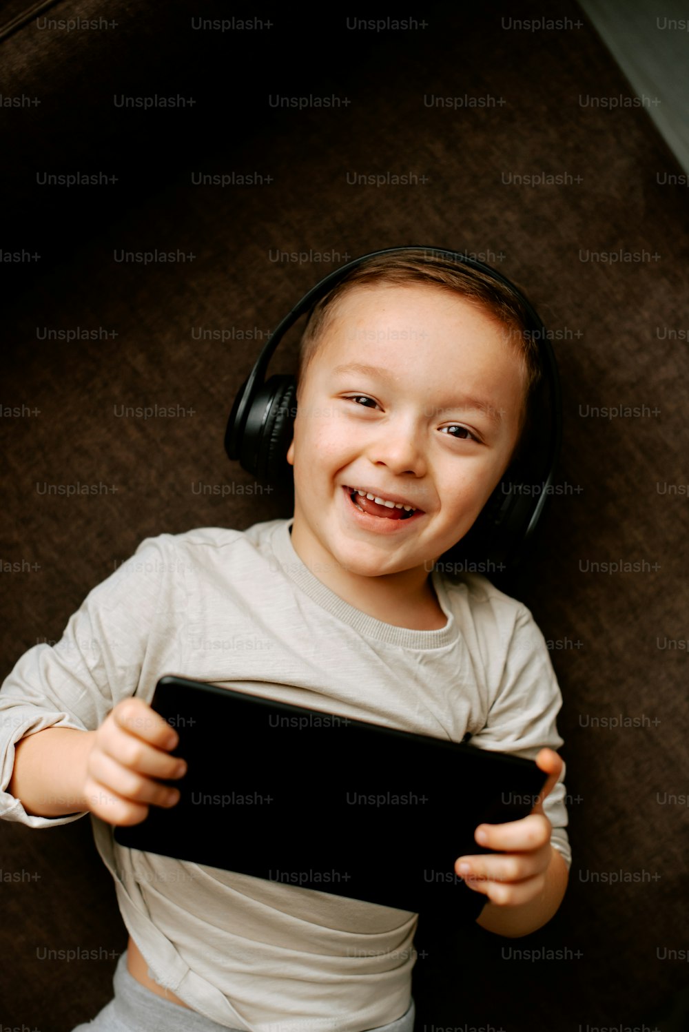a young boy wearing headphones and holding a tablet